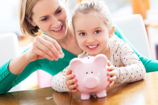a woman and a little girl holding a pink piggy bank.